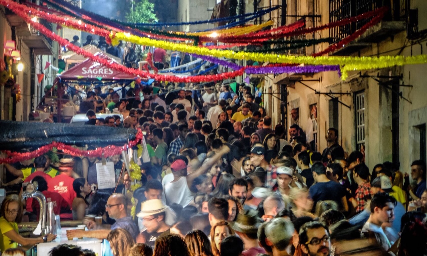 A Lisbon street at night during Santos Populares — crowds, decorations and the unmistakable arraial atmosphere