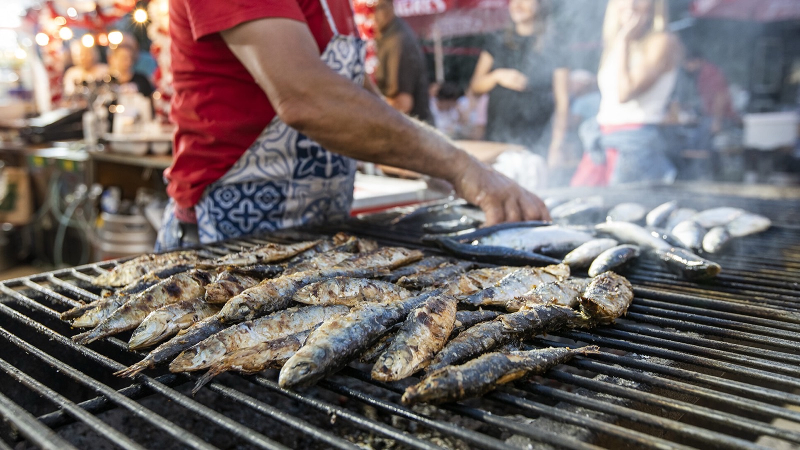 Sardines grilling over charcoal at a Lisbon arraial during Santos Populares
